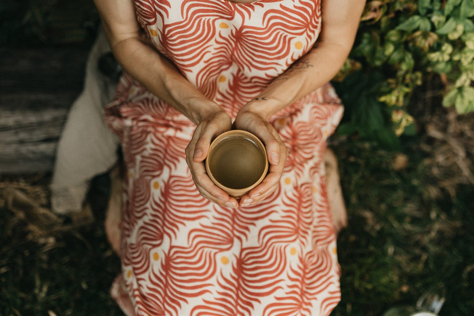 Julie Gautier tenant une tasse entre ses mains, assise au jardin